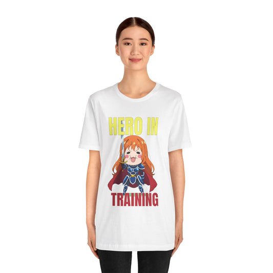 Anime hero t-shirt featuring a chibi knight girl in oversized blue armor with a red cape, holding a small sword with a proud expression. Above her, bold yellow and red text reads “Hero in Training,” giving the design a playful, motivational feel. The artwork is bright, cute, and anime-inspired, making this shirt perfect for gamers, otaku, or anyone who sees life as an ongoing quest. A cozy, encouraging tee for daily wear and leveling up in style.